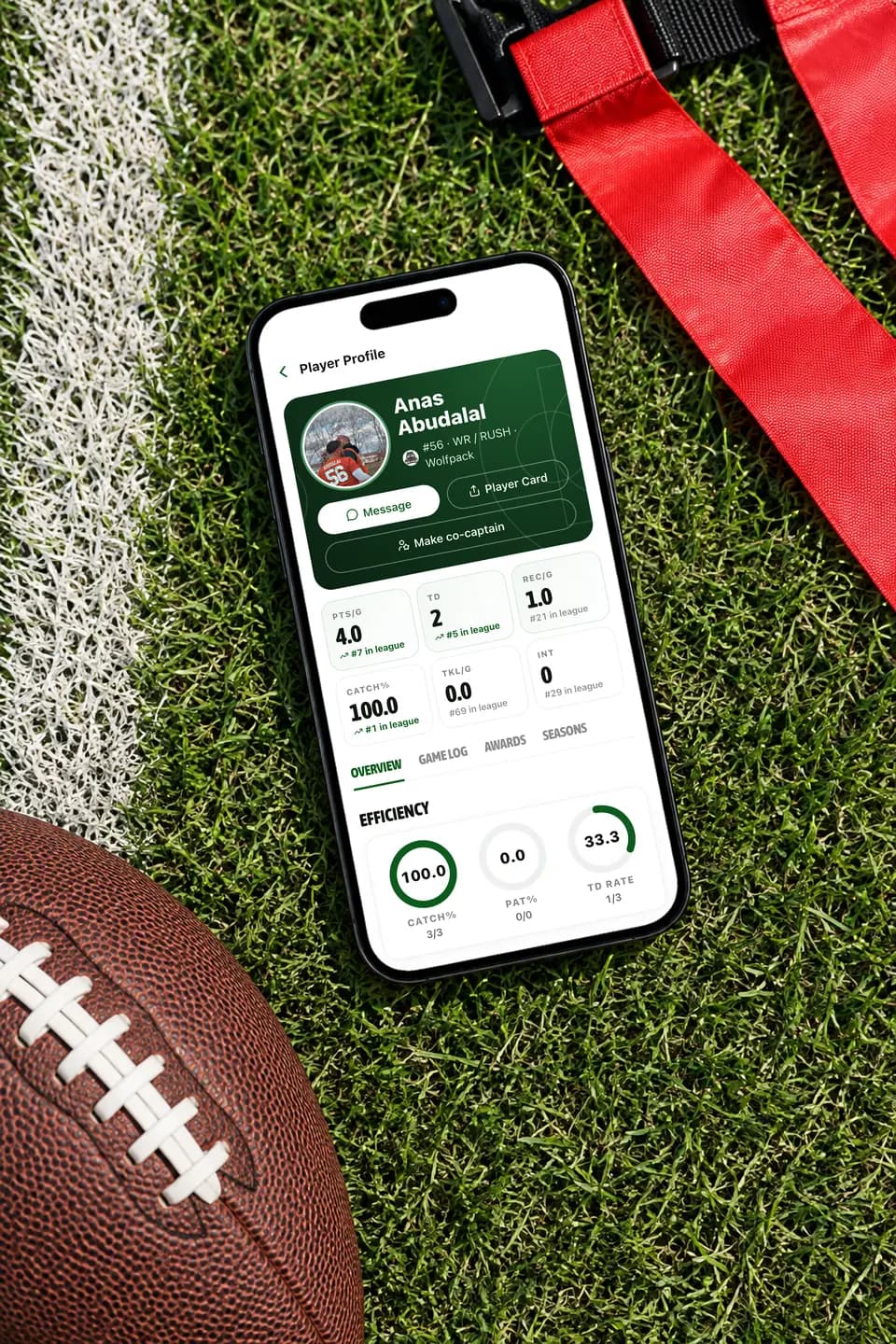 GameGrid player profile on an iPhone on grass beside a football